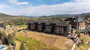 A multi-story hotel with a central courtyard, surrounded by a mountainous landscape. - AMB207 | New Luxury Complex | Hot Tub | Pool | Walk to Base (Steamboat Springs)
