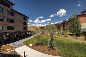 A modern building with a covered walkway and a landscaped courtyard with trees and a pathway. - AMB207 | New Luxury Complex | Hot Tub | Pool | Walk to Base (Steamboat Springs)