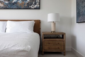 A bedroom with a bed, a nightstand with a lamp, and a painting on the wall. - AMB207 | New Luxury Complex | Hot Tub | Pool | Walk to Base (Steamboat Springs)