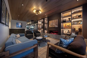 A modern living room with a fireplace, comfortable seating, and a bookshelf filled with decorative items. - AMB210 | Steamboats Newest Luxury Complex | A/C | Hot Tub | Pool | Walk to Skiin (Steamboat Springs)
