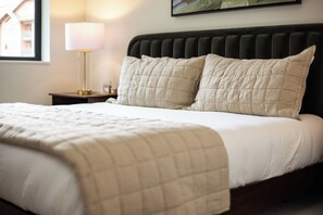 A neatly made bed with a quilted bedspread and two pillows, a bedside lamp, and a framed picture on the wall. - AMB305 | New Luxury Complex | Pool | Hot Tub | A/C | Walk to Slopes (Steamboat Springs)