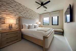 Een slaapkamer met een bed, nachtkastjes, een plafondventilator, een raam met uitzicht en een aan de muur bevestigde televisie.