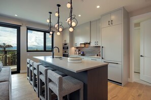 Een moderne keuken met een centraal eiland, roestvrijstalen apparatuur en een groot raam met uitzicht.