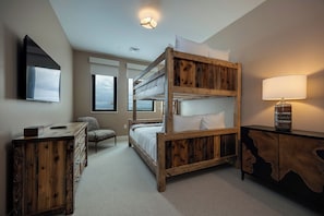 Un lit superposé avec une structure en bois, un bureau avec des tiroirs, une chaise, une lampe et une fenêtre donnant sur un beau paysage.