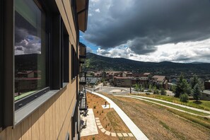 Een modern gebouw met een balkon dat uitkijkt op een stad en bergen.
