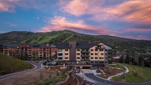 A multi-story hotel with a modern architectural design, situated in a hilly area with a view of the mountains. - AMB402 | Brand New Luxury Complex | Pool | Hot Tub | A/C | Winter Shuttle (Steamboat Springs)