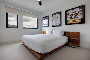 A bedroom with a large bed, a wooden headboard, a nightstand, and three framed sports jerseys on the wall. - AMB402 | Brand New Luxury Complex | Pool | Hot Tub | A/C | Winter Shuttle (Steamboat Springs)