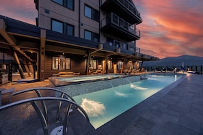Ein modernes Hotel mit Dachpool, Sitzgelegenheiten im Freien und Blick auf die Berge.