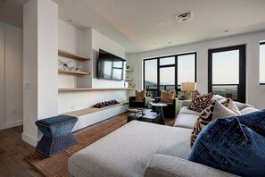A modern living room with a flat-screen TV, comfortable seating, and a large window offering a view. - AMB410 | Steamboat's Newest Luxury Complex | Pool | Hot Tub (Steamboat Springs)