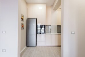 A modern kitchen with a built-in refrigerator, oven, and microwave. - Luxurious Panoramic Apartment (Tiranë)