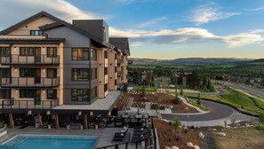 A multi-story hotel with a pool area, outdoor seating, and a view of the surrounding landscape. - Steamboats AMB104 | Newest Luxury Complex | Pool | A/C (Steamboat Springs)