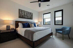 A bedroom with a bed, bedside lamps, a chair, and a ceiling fan. - Steamboats AMB104 | Newest Luxury Complex | Pool | A/C (Steamboat Springs)