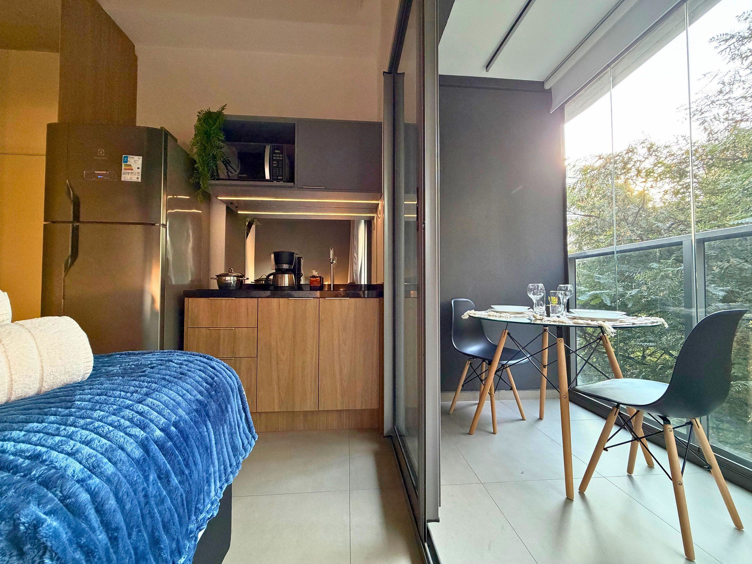 Un dormitorio compacto con cama, kitchenette y comedor con mesa y sillas.