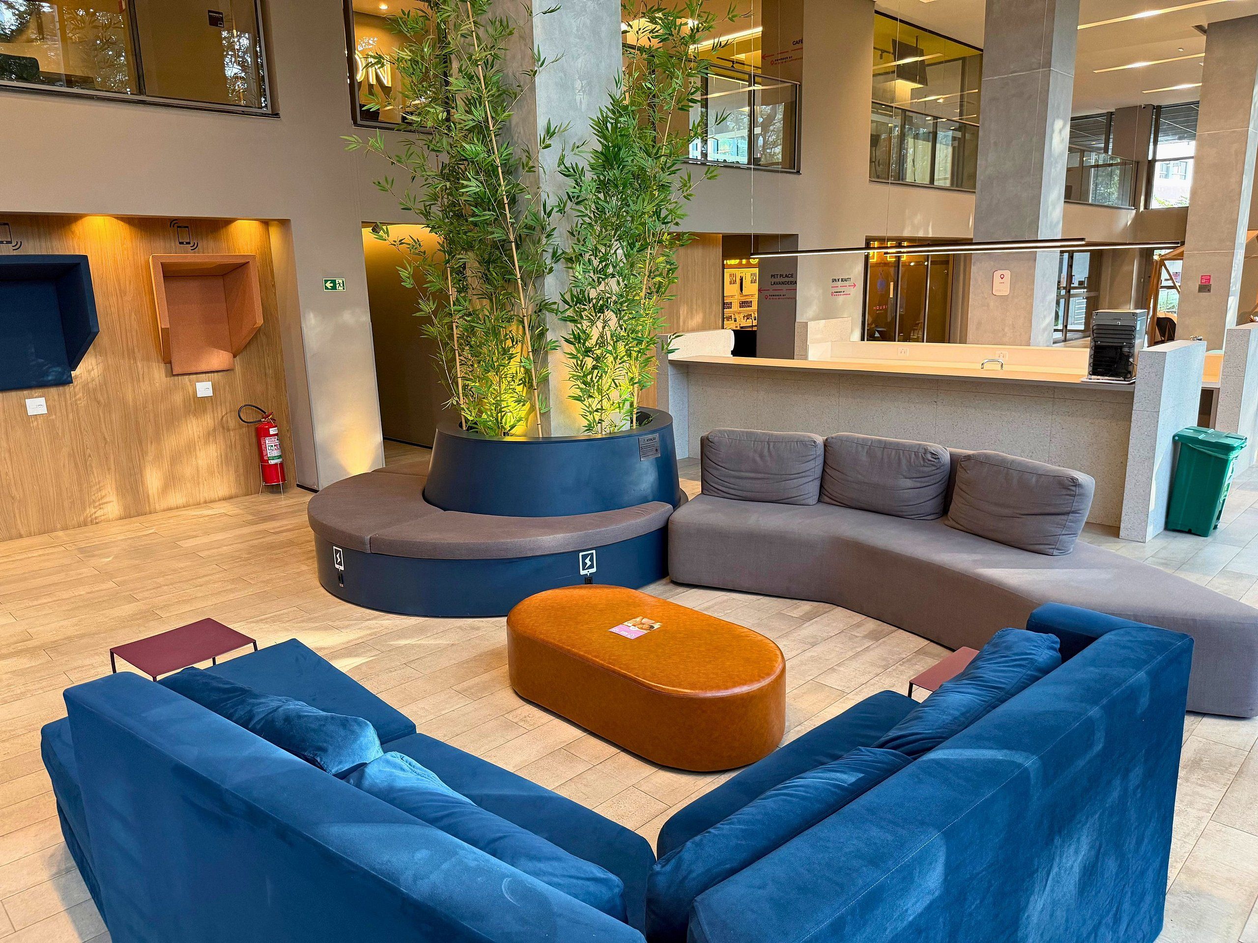 Een moderne lobby met een gebogen zithoek, een receptiebalie en een brandblusser.