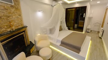 Un dormitorio moderno con cama, chimenea y zona de estar.