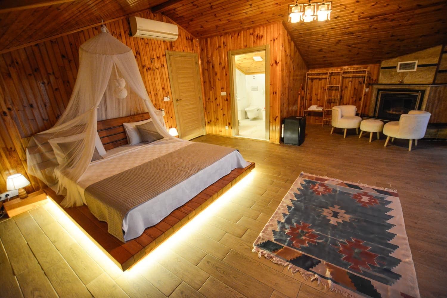 Une chambre confortable, aménagée dans un chalet en bois, avec un lit, un tapis et une cheminée.