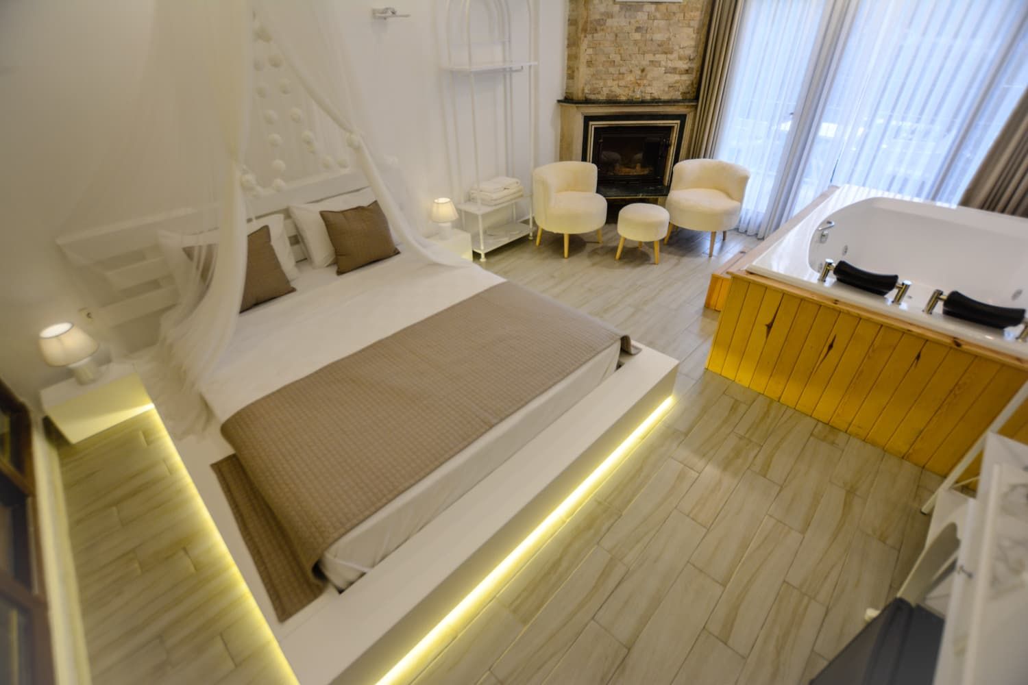 Un dormitorio moderno con una cama grande, mesitas de noche, chimenea y un área de baño separada.