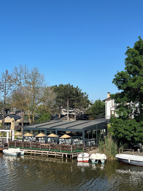 Un restaurante a la orilla del lago con terraza y barcos.