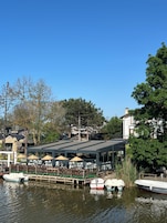 Un restaurante a la orilla del lago con terraza y barcos.