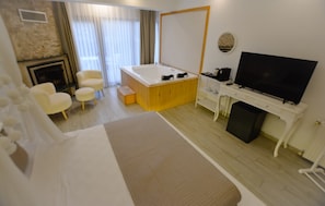 A hotel room with a bed, a desk with a television, a small seating area with chairs, and a fireplace. - My Dream Otel Ağva (şile)