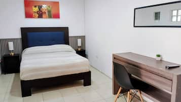Quarto com cama, mesas de cabeceira, escrivaninha e uma cadeira.