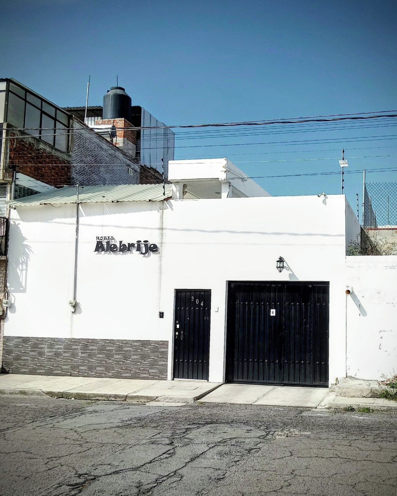 Un edificio con un letrero que dice 'Hotel Alebrije' y dos puertas negras.