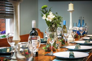 Una mesa de comedor dispuesta con platos, vasos y un florero.