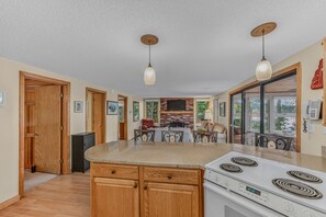 A kitchen with wooden cabinets, a built-in stove, and pendant lighting. - Waterfront | Dock + Dog Friendly | Crystal Lake (Gilmanton)
