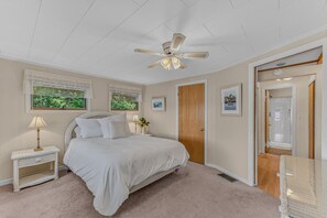 A bedroom with a bed, a nightstand, a lamp, a ceiling fan, and a door leading to another room. - Waterfront | Dock + Dog Friendly | Crystal Lake (Gilmanton)
