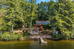 A lakeside cabin with a dock, surrounded by dense forest. - Waterfront | Dock + Dog Friendly | Crystal Lake (Gilmanton)