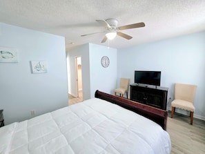 A bedroom with a bed, a ceiling fan, a television, and a chair. - 1 Block to Beach | 3BR Gulf Shores Home, Sleeps 8 (Gulf Shores)