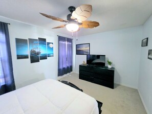 A bedroom with a bed, a dresser, a ceiling fan, and wall-mounted artwork. - Pirate’s Hideaway  3B/2.5B  Sleeps 8 Beach 1 Block (Gulf Shores)