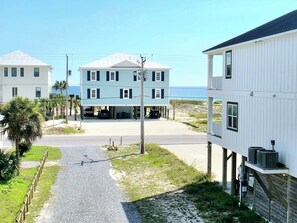 Zona residencial a la costa amb una casa de dues plantes, un garatge, un carrer pavimentat i vistes a l'oceà.