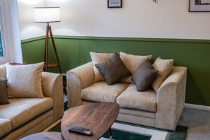 A living room with a beige sofa, a wooden coffee table, and a floor lamp. - Modern home, ideal for long stays Free Parking (West Sussex)