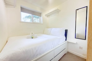 A bedroom with a bed, a window, a mirror, and a wall-mounted shelf. - Cosy Horsham 1-Bed · Free Parking · Walk to Town (Horsham)