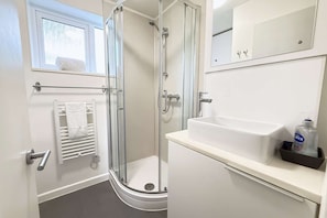 A modern bathroom with a glass shower enclosure, a white sink, and a towel rack. - Cosy Horsham 1-Bed · Free Parking · Walk to Town (Horsham)