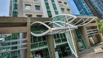 Een modern gebouw met een glazen gevel en een opvallend wit architectonisch element ervoor.