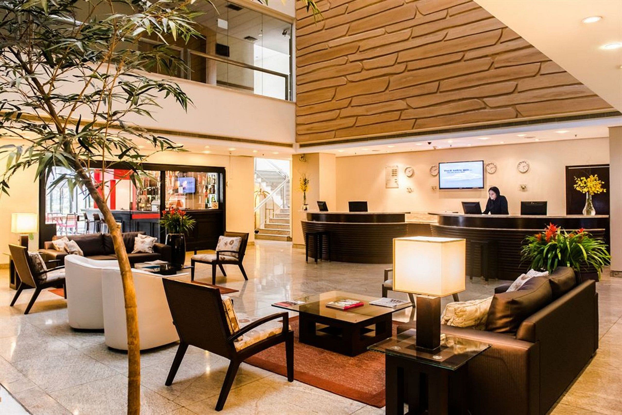 Un hall d’hôtel comprenant un comptoir d’accueil, un espace salon et un escalier menant à un étage supérieur.