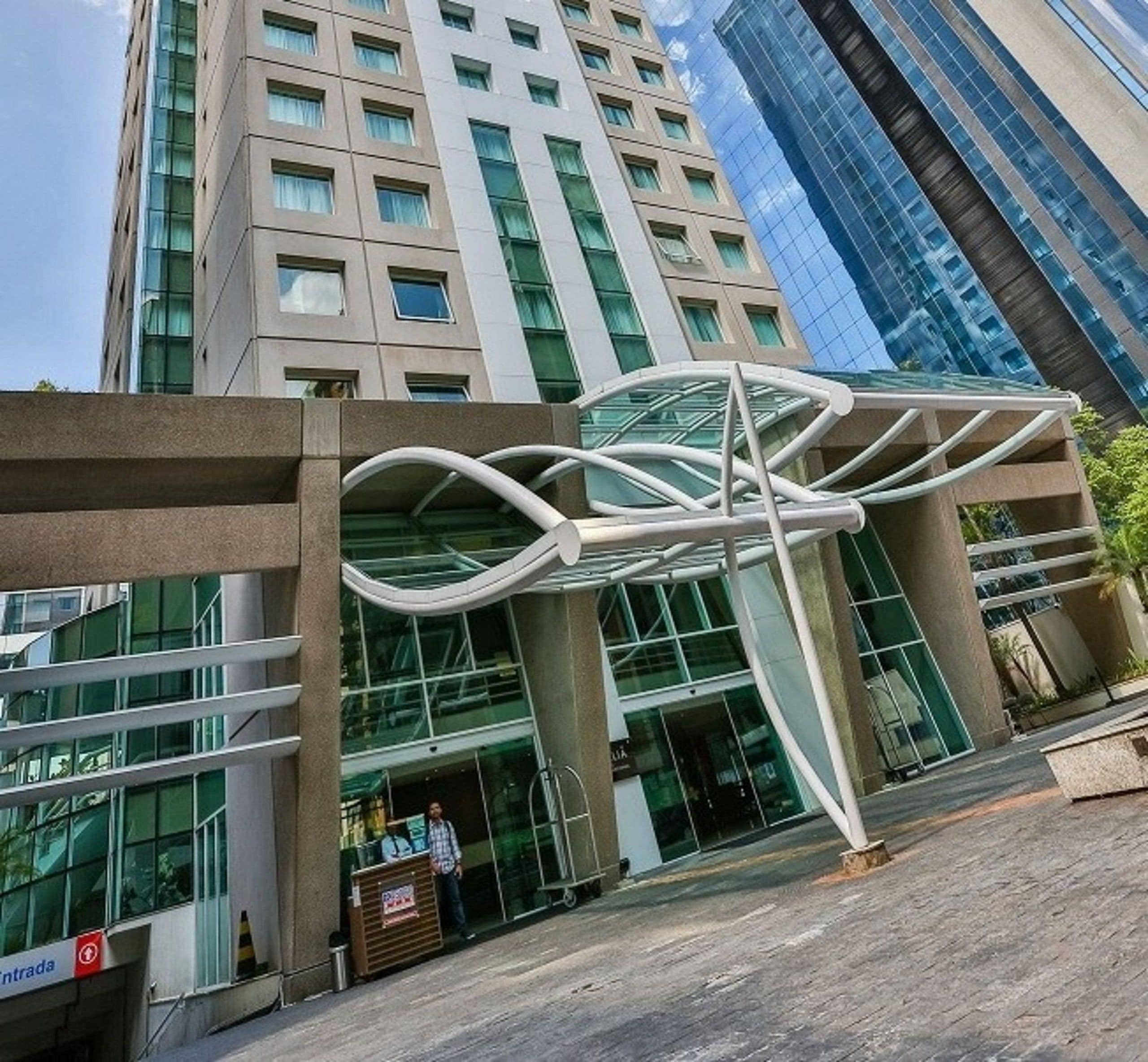 A modern building with a glass facade and a distinctive white architectural feature in front.