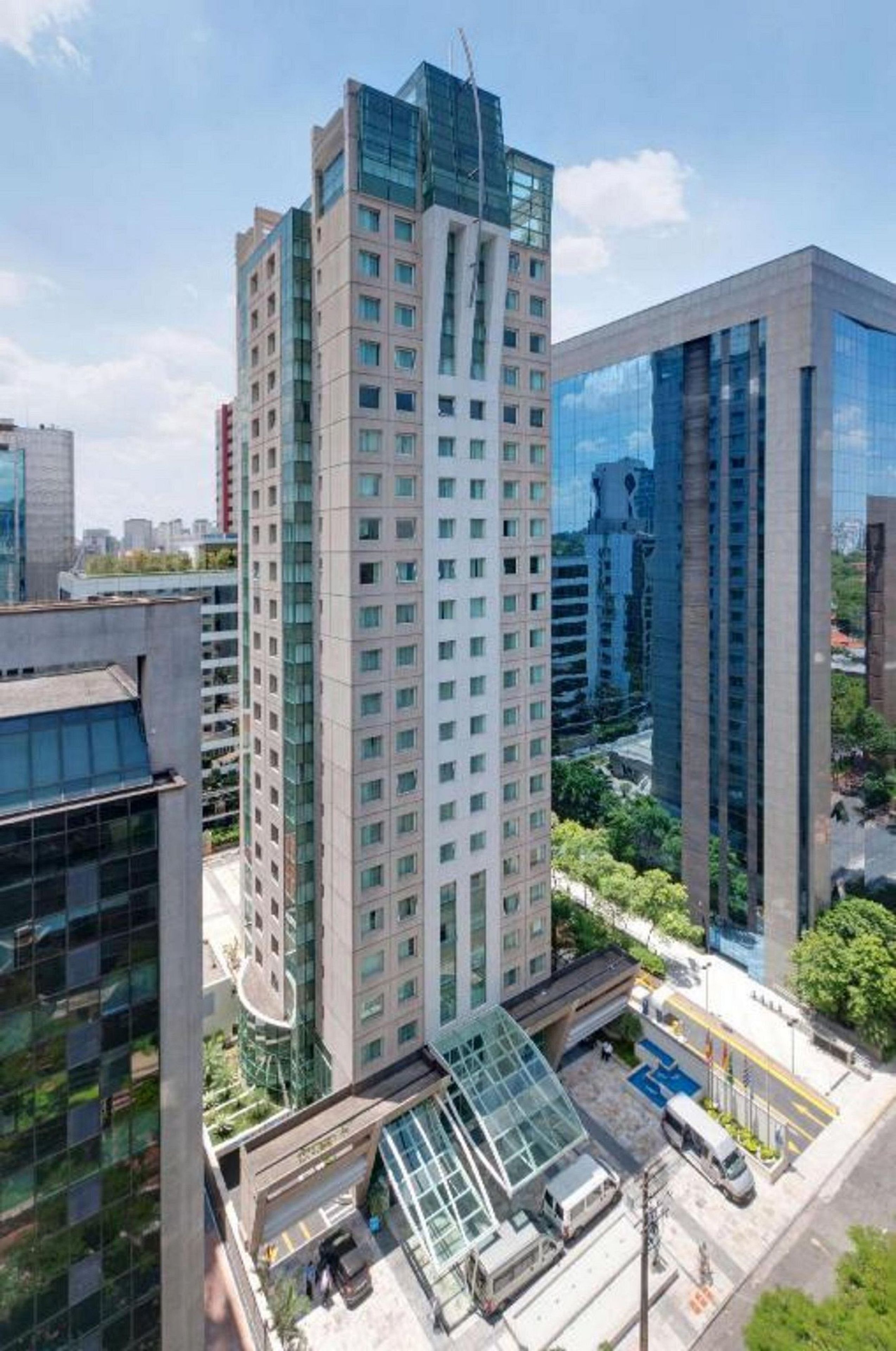 Un edificio alto con varios pisos y fachada de vidrio, rodeado de otros edificios modernos.