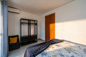 Un dormitori amb un llit superposat, un armari, una porta i un llit amb un estovat estampat.