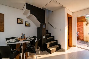 A modern interior with a dining area, a staircase, and a view of the outside. - Casa com Churrasqueira a 290 Metros da Roddertown (Balneário Camboriú)