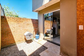 Una zona de pati moderna amb pared de maó, una barbacoa i un escalfador d'aigua.