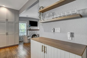 Eine moderne Küche mit weißen Schränken, einer Holz Arbeitsplatte und einer eingebauten Ablage für Weingläser.