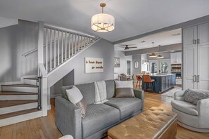 Ein modernes Wohnzimmer mit einem grauen Sofa, einem Couchtisch und einer Treppe mit einer weißen Geländer.