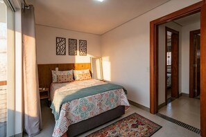 Ein Schlafzimmer mit Bett, Nachttisch, Spiegel und einer Tür zu einem anderen Raum.