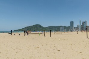 A beach with volleyball nets, a sandy area, and a cityscape with tall buildings in the background. - Casa c Churrasqueira e Wi-fi Perto do Roodertown (Balneário Camboriú)