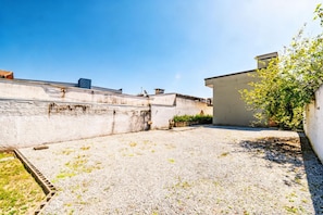 A rooftop with a gravel surface, a white wall, and a small garden area with a tree. - Casa c Churrasqueira e Wi-fi Perto do Roodertown (Balneário Camboriú)