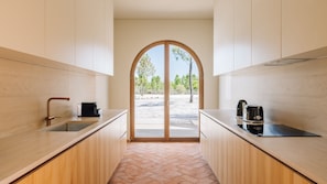 A modern kitchen with a central island, a sink, and a stove. - Ando Living - Comporta Villas - Villa 3 (Carvalhal)