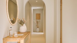 A hallway with a wooden console table, a mirror, and two vases with dried flowers. - Ando Living - Comporta Villas - Villa 9 (Carvalhal)